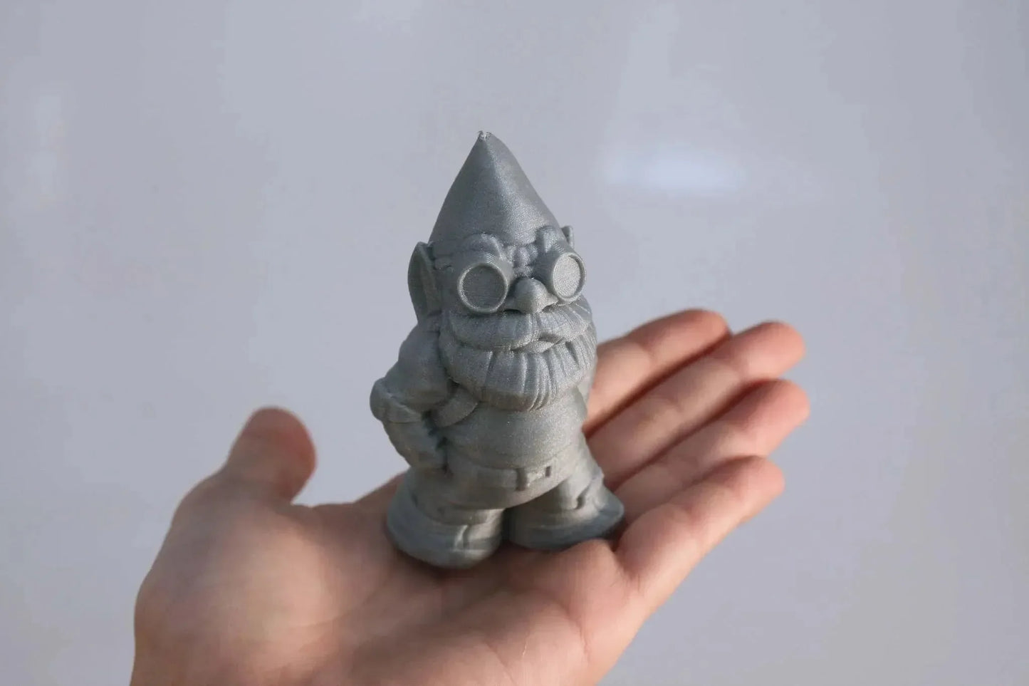 Miniatura gnomo stampata in 3D grigia su una mano, dettaglio stampa 3D artigianale
