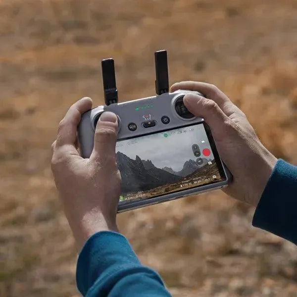 Radiocomando drone DJI RC 2 con schermo integrato in uso all'aperto, ripresa paesaggio montano