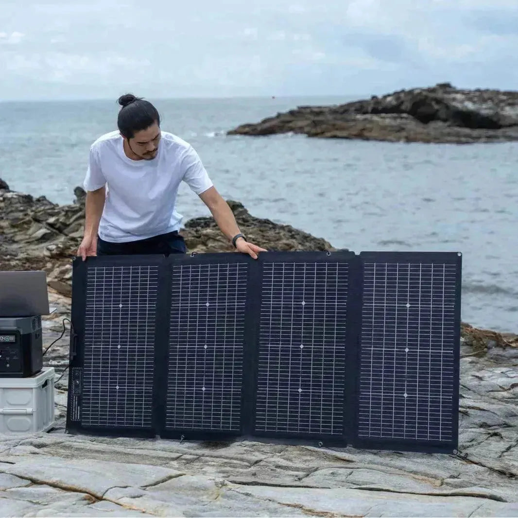Uomo all’aperto installa pannello solare bifacciale pieghevole 220W su scogliera vicino al mare
