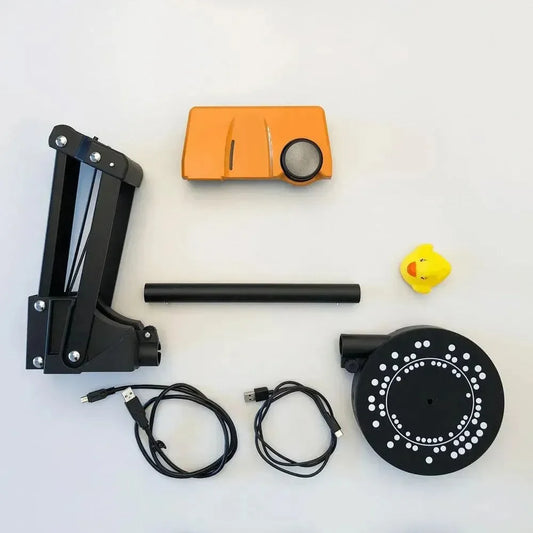 Kit scanner 3D con componenti, cavi USB e oggetto campione su sfondo bianco