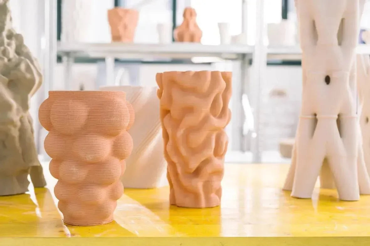 Vasi in ceramica dal design organico stampati con stampante 3D su tavolo giallo